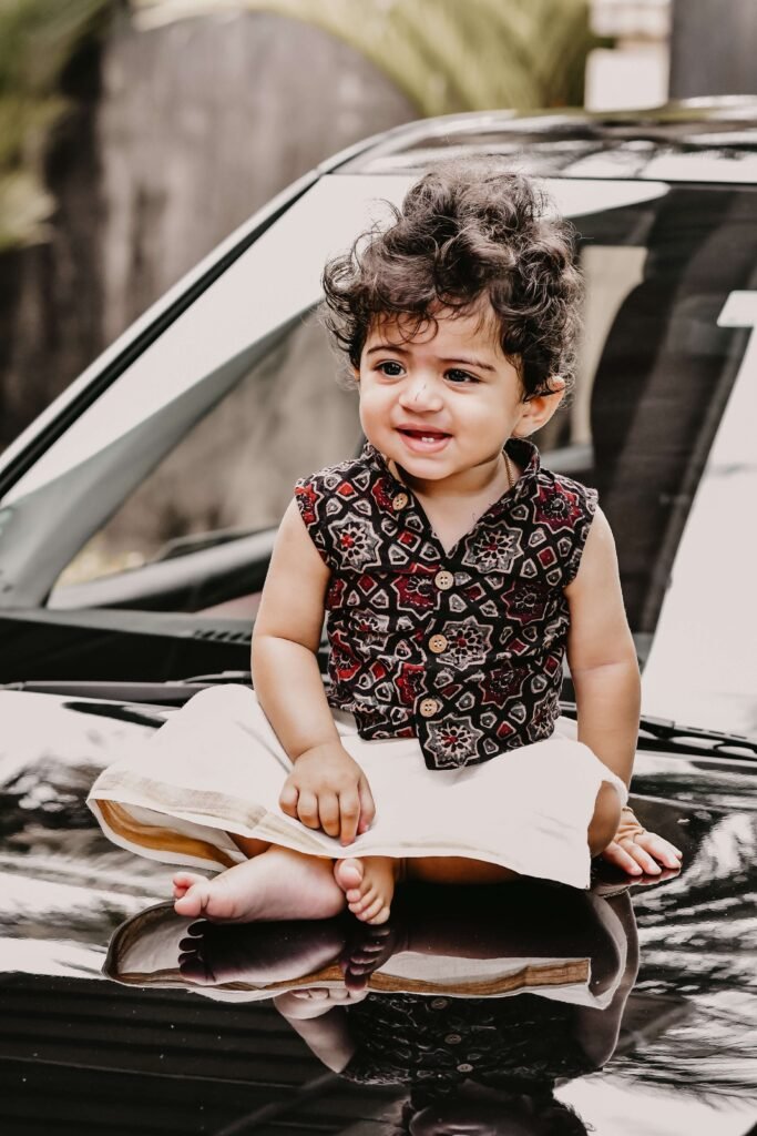 Infant on the hood of a car