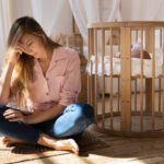 Postpartum mother next to her baby in a crib